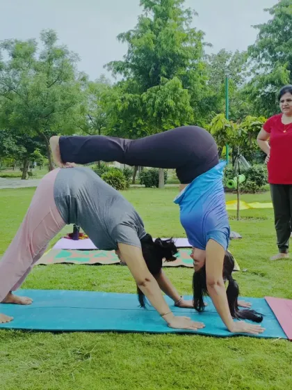 Partner yoga in the park is a beautiful way to connect with another person and with nature. This Acro Yoga pose, a supported downward dog and handstand variation, builds strength, balance, and a great deal of trust between partners.