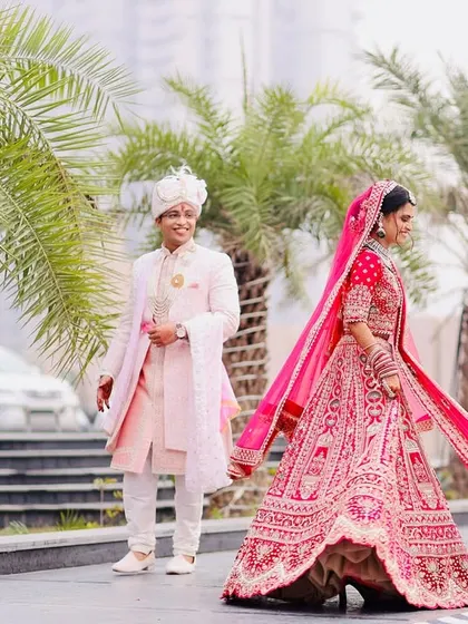 A playful and candid shot of the bride walking ahead while the groom follows, capturing the flowing movement of her dupatta and their happy interaction.