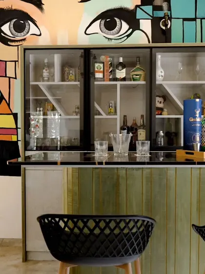 We designed this vibrant bar area as part of an informal living space. The custom mural adds a bold artistic statement, while the fluted wood bar and modern stools create a stylish spot for entertaining.