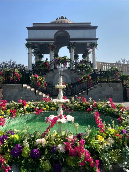 A stunning fountain surrounded by a riot of colorful flowers, creating a vibrant and refreshing centerpiece for an outdoor celebration at a palace venue.