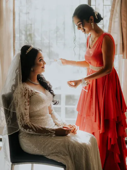 A sweet moment between the bride and her bridesmaid, who helps with the final touches on her veil.