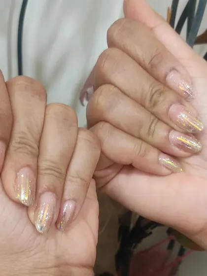 A full set of nails with a shattered glass effect using gold holographic foil over a natural, sheer base.