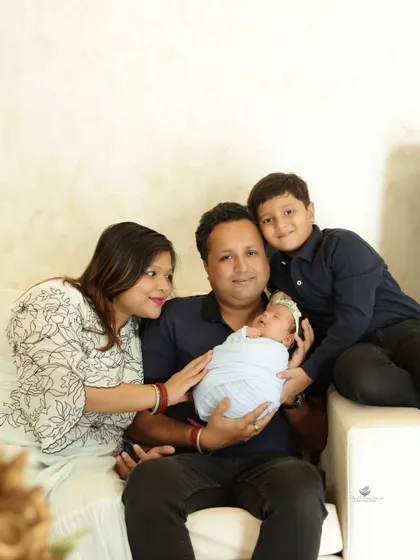 A beautiful portrait of a family of four. The parents and older brother look lovingly at the newest addition, their newborn baby girl.