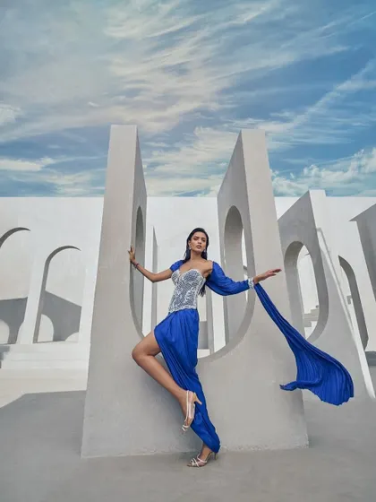 A pre-draped sari in a striking active blue hue, crafted from crushed fabric and elevated with delicate pearl embellishments. A statement in motion, designed for the contemporary muse.
