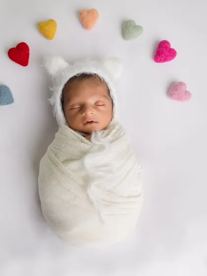 A minimalist and adorable setup with a simple white wrap and a rainbow of felt hearts. The bear bonnet adds a touch of whimsy.