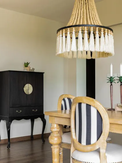A classic black bar cabinet with cabriole legs adds a touch of vintage elegance to this dining space. It's paired with a beaded chandelier for a coastal-glam look.