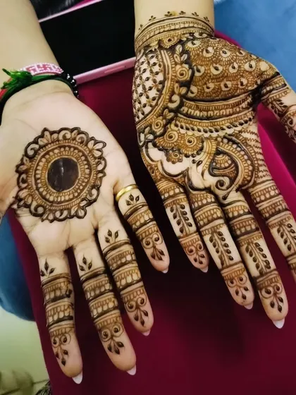 An example of asymmetrical mehendi for a party. One hand has a full, intricate design while the other has a simple, bold mandala.
