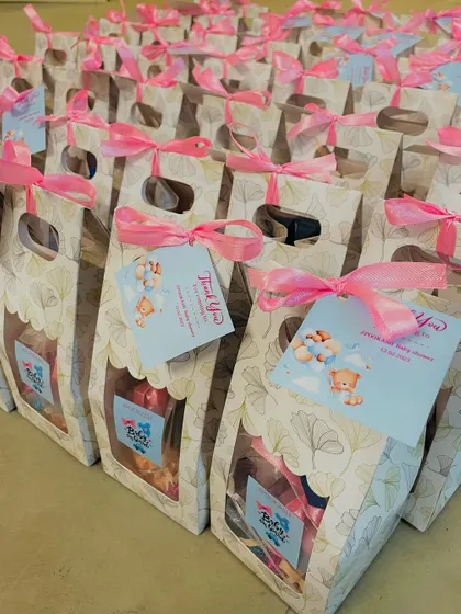 A row of our "Pookash" baby shower favors, each with a custom tag and a mix of goodies inside.