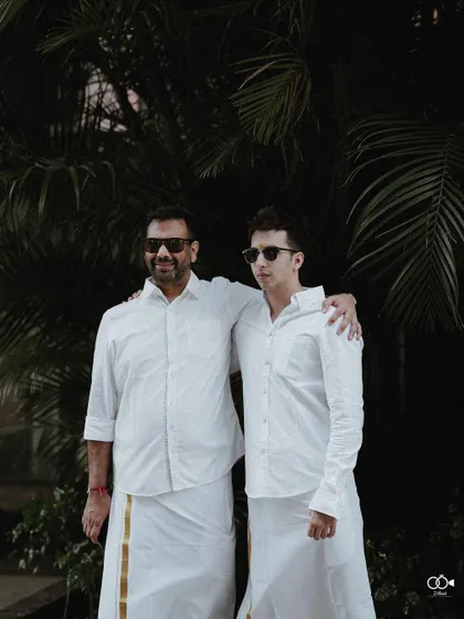 A cool portrait of two male family members in traditional white veshtis and sunglasses.