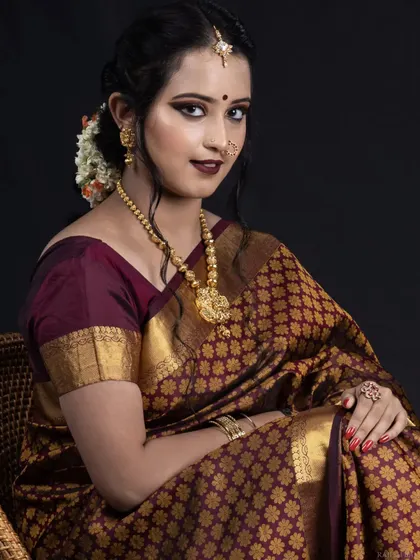 A classic portrait of a South Indian bride. This look features a bold, dark lip and defined smokey eyes, creating a dramatic and regal effect that is perfect for evening ceremonies or portfolio-style wedding photos.