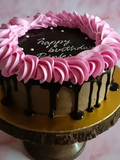 A simple yet elegant chocolate drip cake with pink frosting, perfect for a birthday.