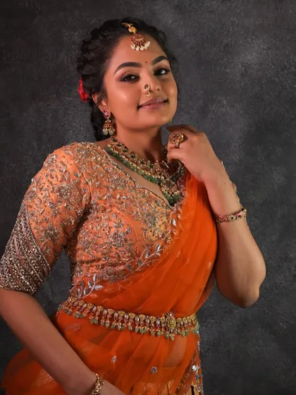 A beautiful engagement look featuring a Kundan necklace with green bead drops. It pairs wonderfully with the peach and orange tones of her lehenga.