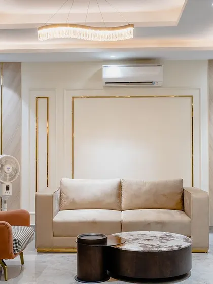 A separate seating area within the bedroom, featuring a small sofa and a marble coffee table. The gold-trimmed wall panels add a touch of elegance.