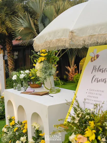 The 'Polaroid Corner' station, complete with a fringed umbrella, fresh flowers, and a sign inviting guests to create memories. It’s a fun, interactive element that also serves as beautiful decor.