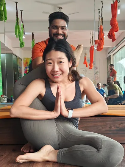 It's wonderful to see students from all over the world find their strength in our shala. Here, I'm assisting with a challenging leg-behind-head pose.