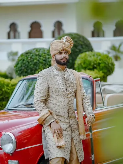 Another angle of the royal groom and his vintage car, this shot offers a clearer view of his magnificent sherwani and confident stance.