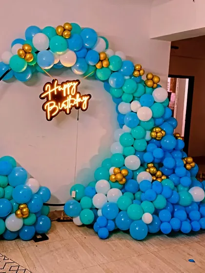 A flowing balloon arch on a ring frame in shades of blue and white with gold accents.