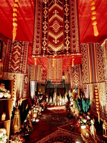 An immersive entrance designed to feel like a vintage Persian bazaar, with walls and ceilings completely covered in rich, patterned rugs and warm lighting from traditional lanterns.