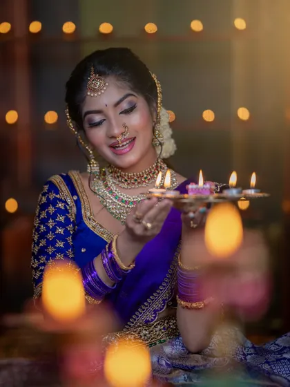 A beautiful look for a Diwali themed shoot. The model is holding a tray of diyas, and her makeup is warm and glowing to match the festival of lights.