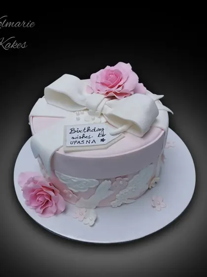 A gift box cake is a timeless design. This one is decorated with a large fondant bow, delicate lace details, and soft pink sugar roses, making it the perfect surprise.