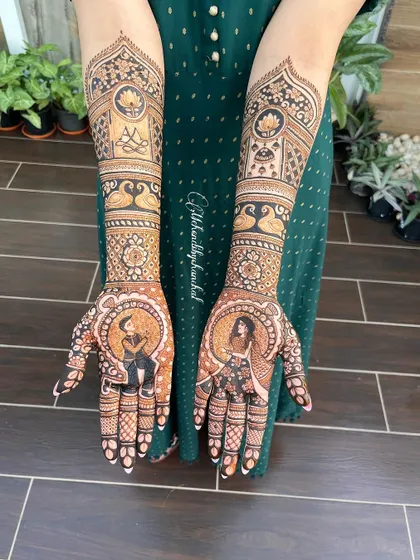 A full view of an engagement mehendi featuring portraits of the couple. The bride's portrait is on one hand and the groom's on the other, ready to come together.