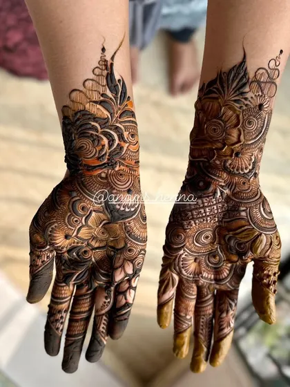 This photo showcases a complete bridal mehndi look. The designs on both hands are perfectly matched, creating a symmetrical and elegant appearance.