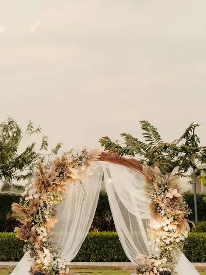 A simple yet beautiful arch for a vow exchange ceremony, adorned with rustic pampas grass and soft florals, creating a perfect frame against the open sky.