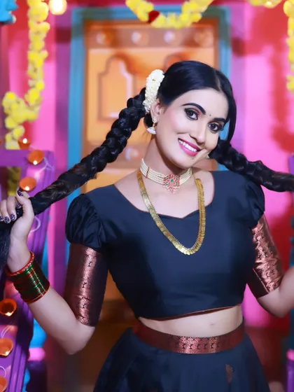 A playful and happy portrait of a model in a traditional black half-saree, showing off her braided hair.
