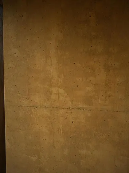 The texture of the earthen wall at the farm pavilion, showing the subtle imperfections that give handcrafted buildings their unique character.