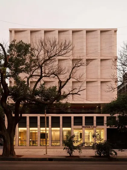The Stone Boulevard building at dusk, framed by trees. The architecture is designed to be a timeless statement, where the elegance of the material and the strength of the form speak for themselves.