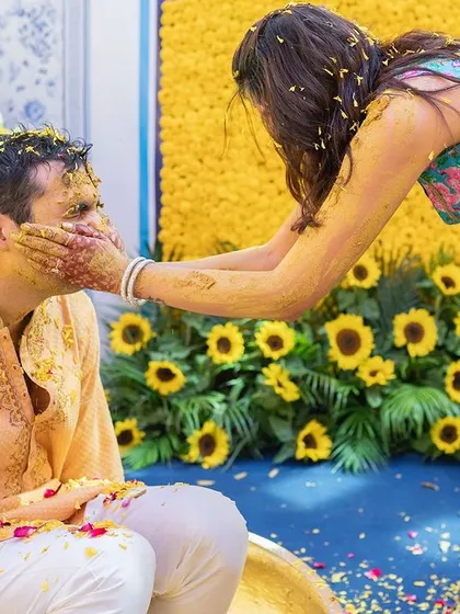 The bride playfully smearing haldi on the groom's face.