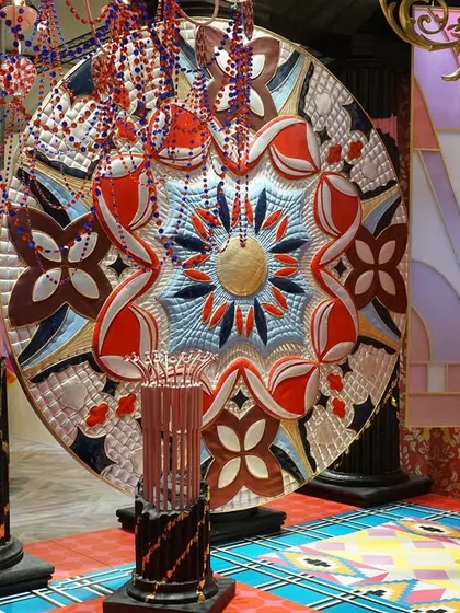 A large, ornate textile medallion from the 'Bad Taste?' installation. This piece, with its bold colors and intricate patterns, is a centerpiece of the exhibit, embodying the audacious and over-the-top aesthetic that challenges quiet luxury.