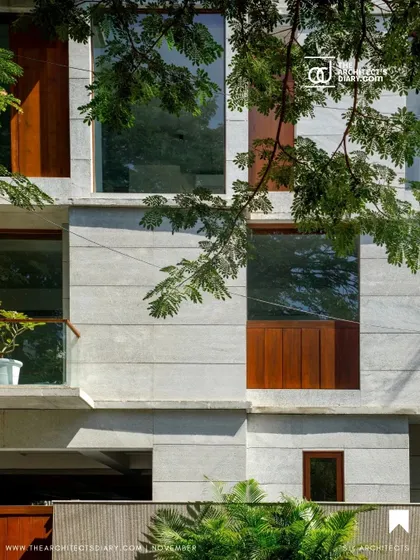A detail of the Boat Club Apartments facade, where the texture of board-formed concrete is juxtaposed with smooth wooden panels and large glass windows, creating a rich material palette.