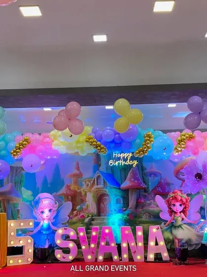 A straight-on view of the fantasy stage setup, showing the arrangement of props, balloons, and the glowing marquee name and number.