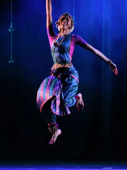 A dynamic leap, full of life and energy. The beautiful blue and purple costume flows with the movement, adding to the visual spectacle.