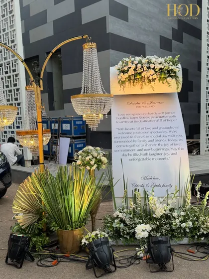 A personalized welcome note for guests, elegantly displayed amidst white floral arrangements and stunning crystal chandeliers. This is a beautiful way to greet your guests and share a message of gratitude.