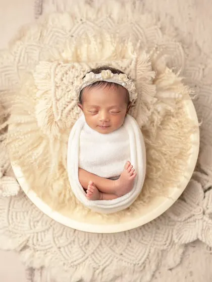 An artistic composition with a newborn nestled in a bowl, surrounded by delicate macrame. This highlights the creative setups I design.