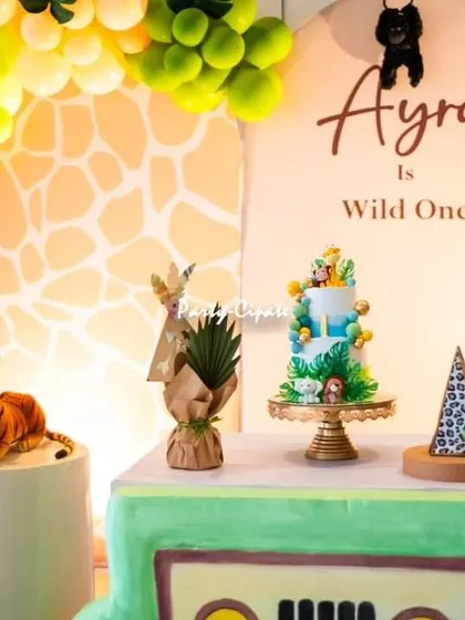 A closer look at Ayra's safari jeep dessert table. The setup includes her 'Wild One' cake, themed props, and a giraffe-print backdrop, all coming together for a cohesive look.