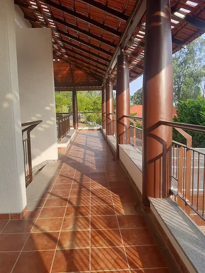 The same corridor, now further along in the construction process. Terracotta tiles have been laid and columns painted, showing the progression from raw structure to a finished, earthy space.
