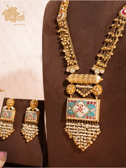 This long antique set captures the essence of royal serenity with turquoise and pearls. The rectangular pendant features intricate Meenakari work in shades of the sea, complemented by cascades of tiny pearls, blending heritage artistry with timeless elegance.