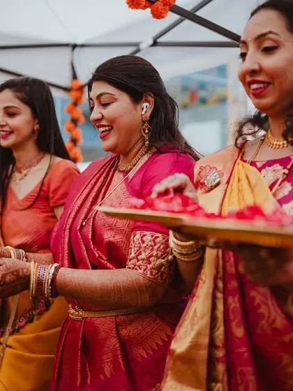 The women of the family, dressed in beautiful sarees, hold plates of rose petals, adding to the color and vibrancy of the event.