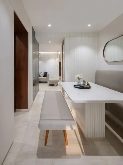 A view from the living area into the dining nook. The consistent use of white walls and light-colored upholstery creates a seamless flow between the spaces.