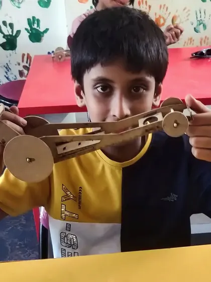 Holding up his completed wooden car, this student is ready to test his creation.