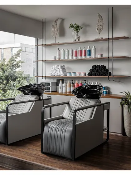 The hair wash station is designed for ultimate relaxation. The ergonomic chairs are set against a large window with views of the outdoors, and open shelving provides stylish and accessible storage for products.