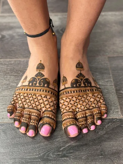A modern take on bridal feet mehendi, with a geometric pattern and elephant motifs on the ankles.