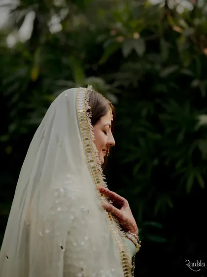 A soft and ethereal profile shot of the bride, Aakruti, her face gently illuminated under her veil.