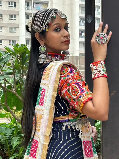 This shot highlights the full set of accessories: a statement ring, cowrie shell cuff, choker, and an elaborate matha patti.