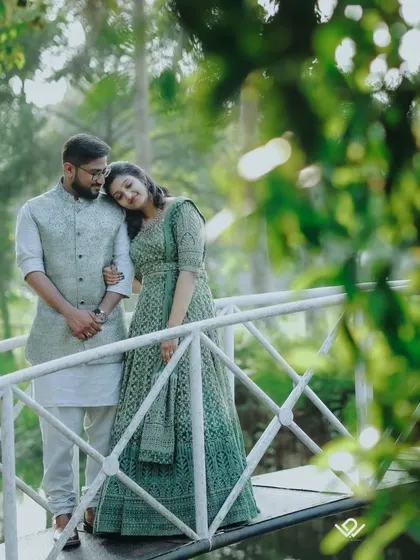 A serene couple portrait on a white bridge over water, framed by green leaves for a natural, intimate feel.