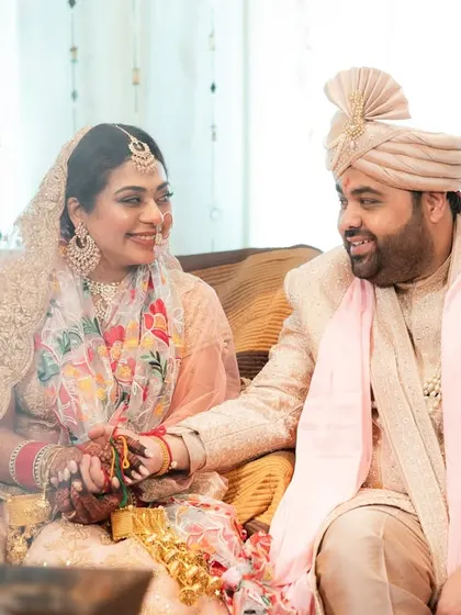 A sweet moment between a couple during their wedding rituals. Their gentle smiles and held hands speak volumes.