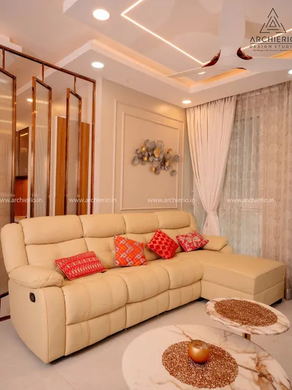 A comfortable living room with a leather recliner sofa and marble-topped coffee tables. The metal partition adds a decorative element while maintaining an open feel.